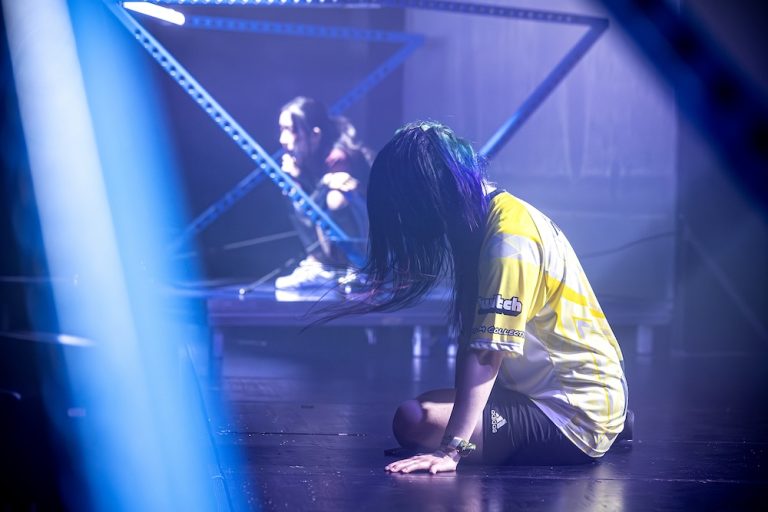 A person with long hair covering their face is sitting in a foggy room.