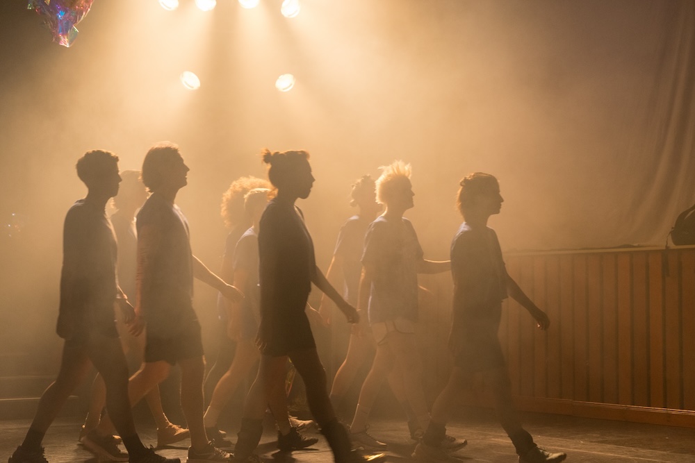 A group of people walking through a foggy room.