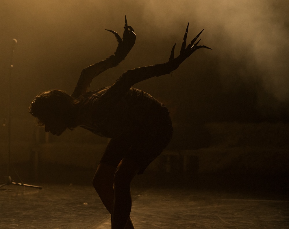 The silhouette of a dancer wearing monster gloves in a foggy room