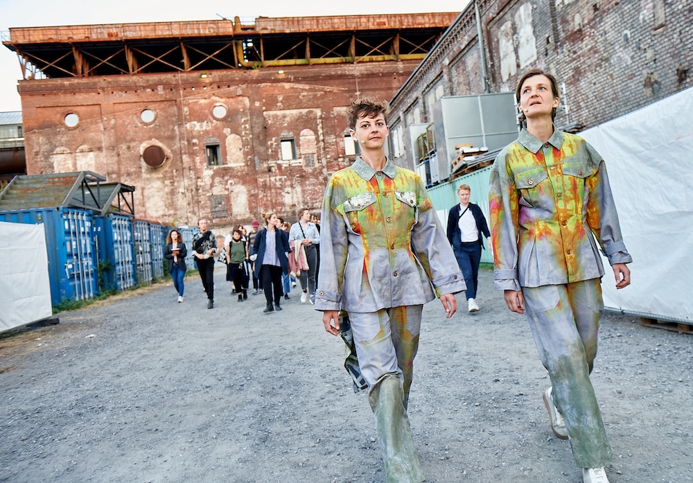 Two musicians in colorful working suits leading a group of audience outdoors